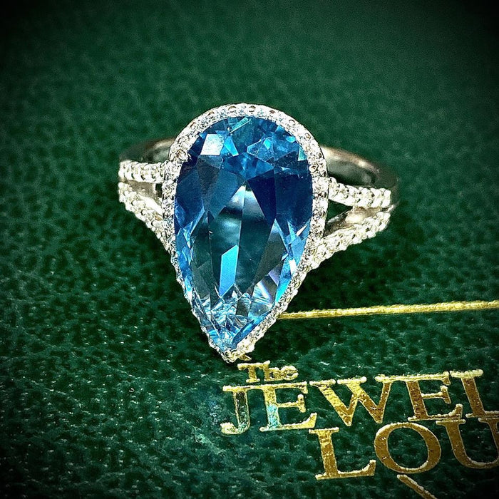 A breathtaking beauty. This mesmerizing halo ring features an exquisite 6.32ctw pear-shaped simulated paraiba tourmaline and simulated diamonds, by Lafonn. The ring is set in sterling silver bonded with platinum. Size 7.