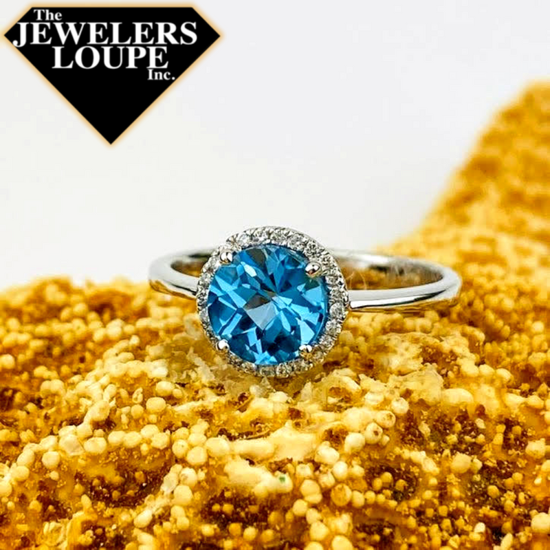 14K White Gold Ring set with 1.55ctw Genuine Blue Topaz surrounded by .10ctw Diamonds.